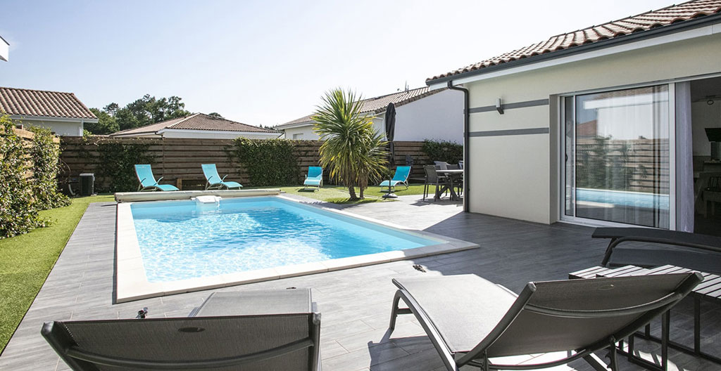 Villa typique d'Hossegor avec façade bois clair, terrasse et vélos, entourée de pins maritimes